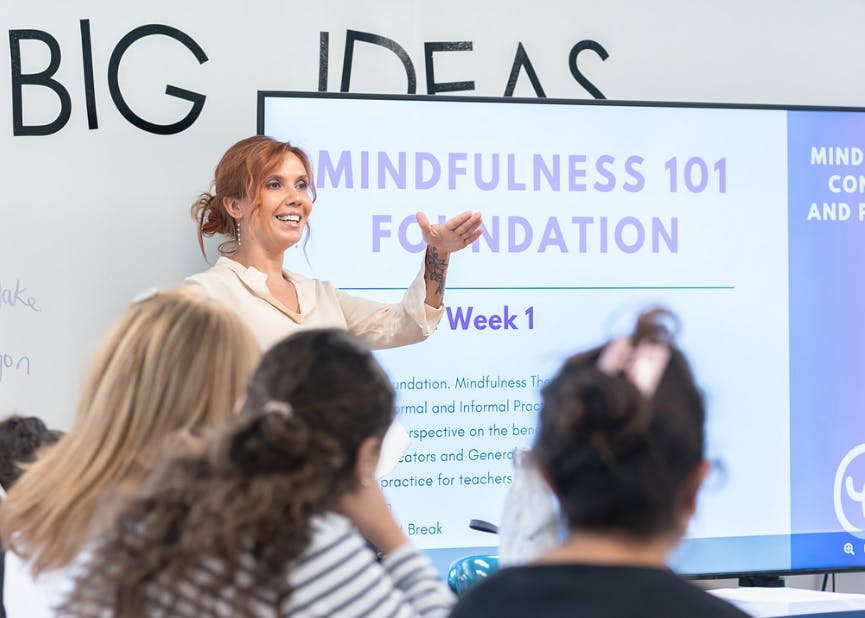 Person presenting in front of a screen displaying "Mindfulness 101 Foundation"