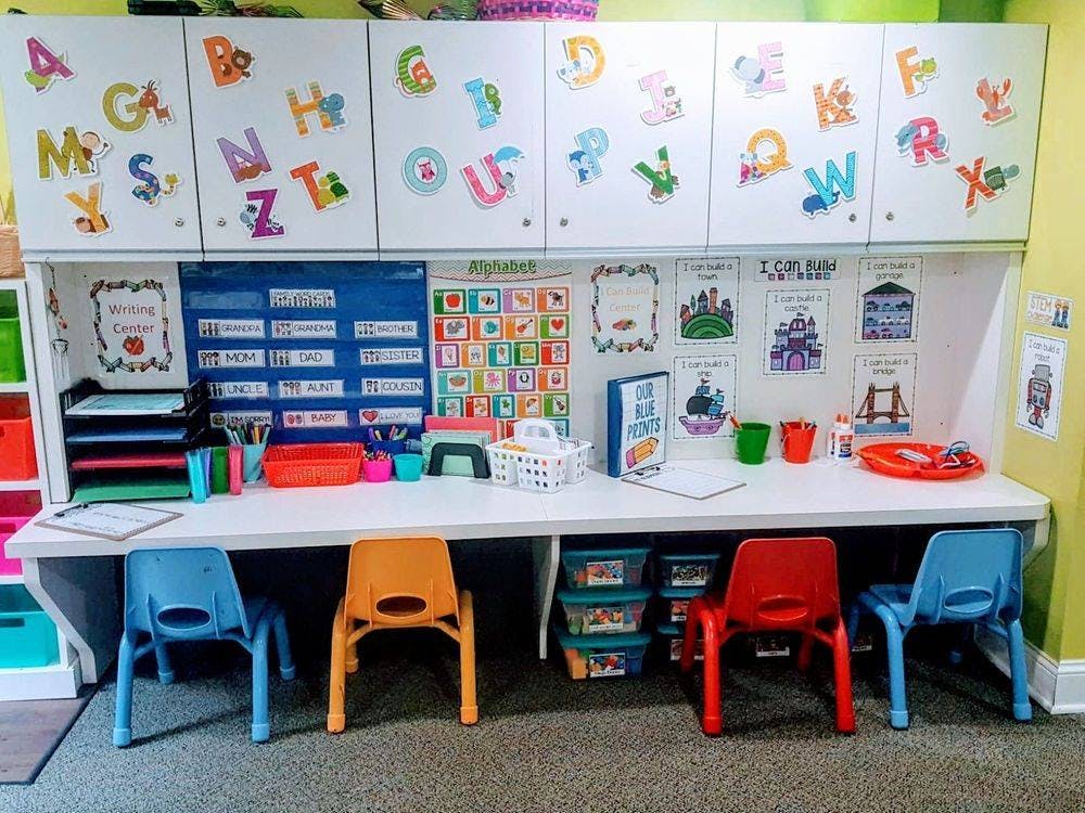 Children's classroom with small chairs and a long desk with learning materials