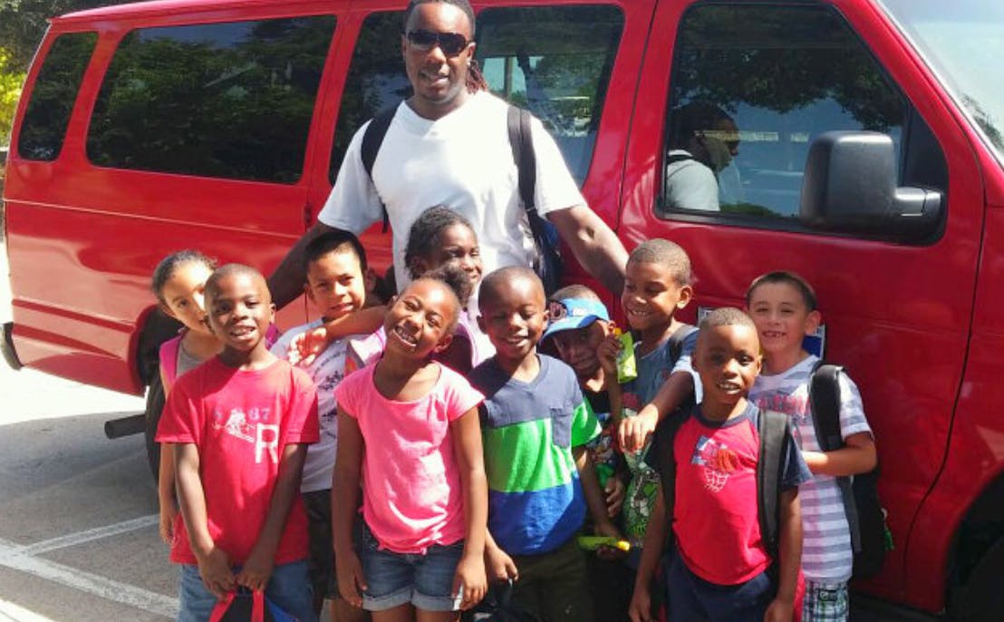 Adult and group of children standing in front of a red van