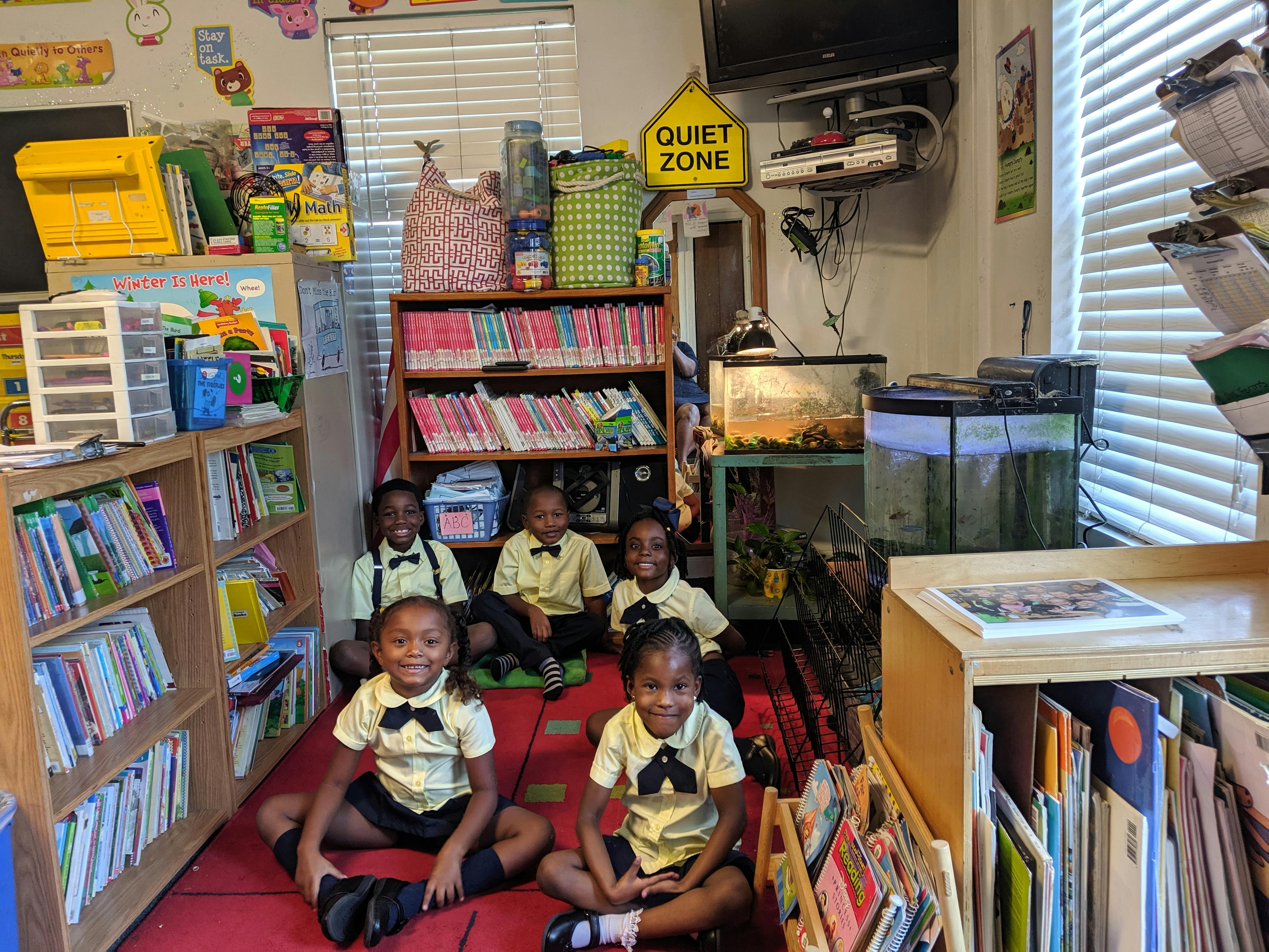 Children in matching outfits sitting on the floor in a classroom