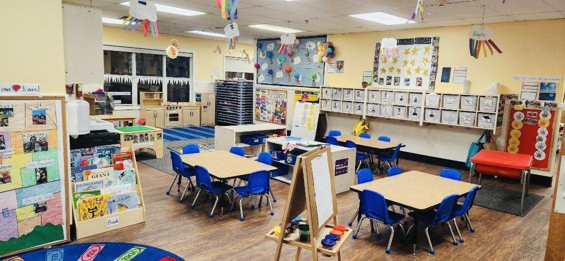 An empty early childhood classroom with small tables and chairs