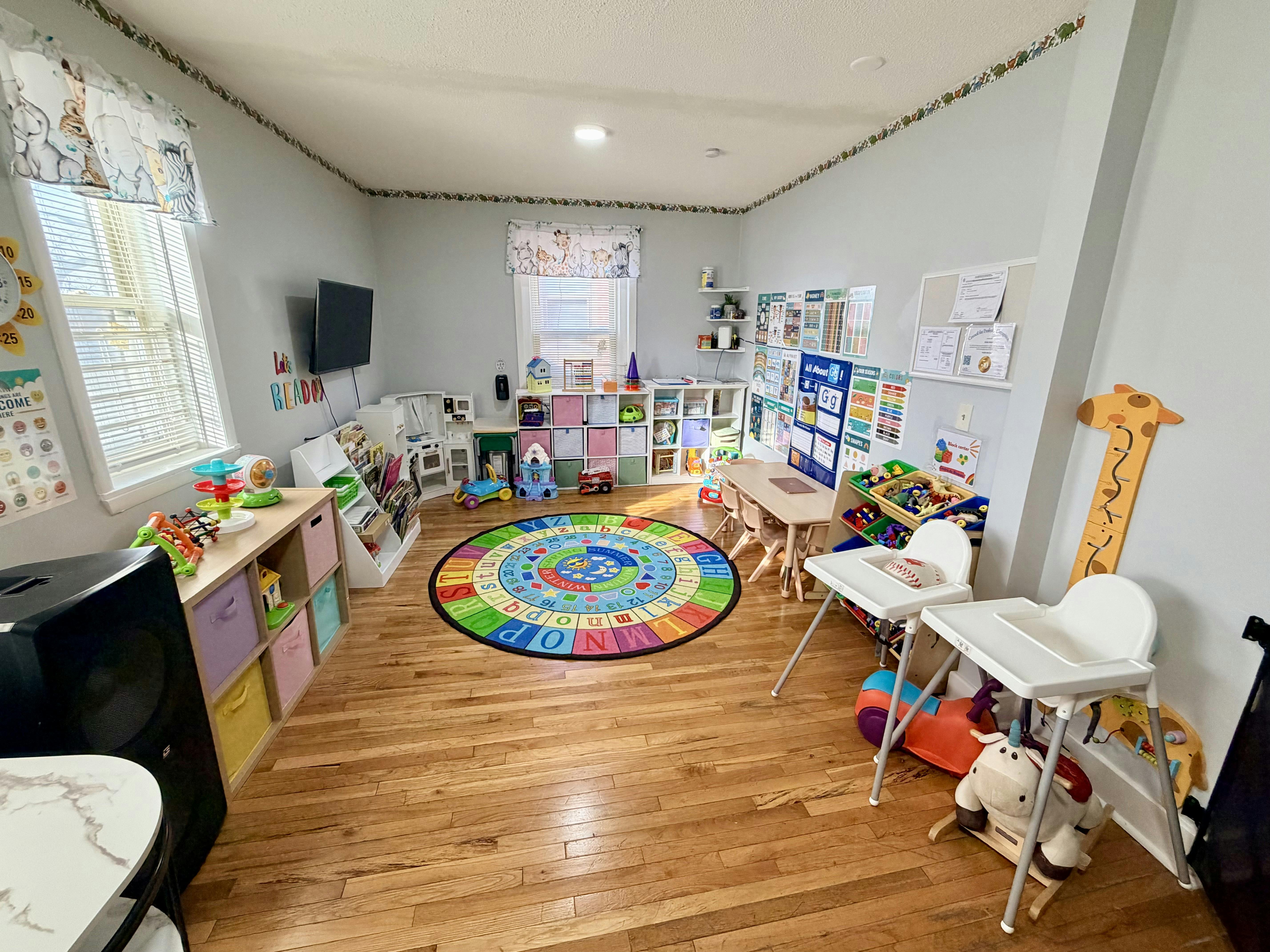 Classroom filled with toys, child-sized furniture, and an alphabet rug