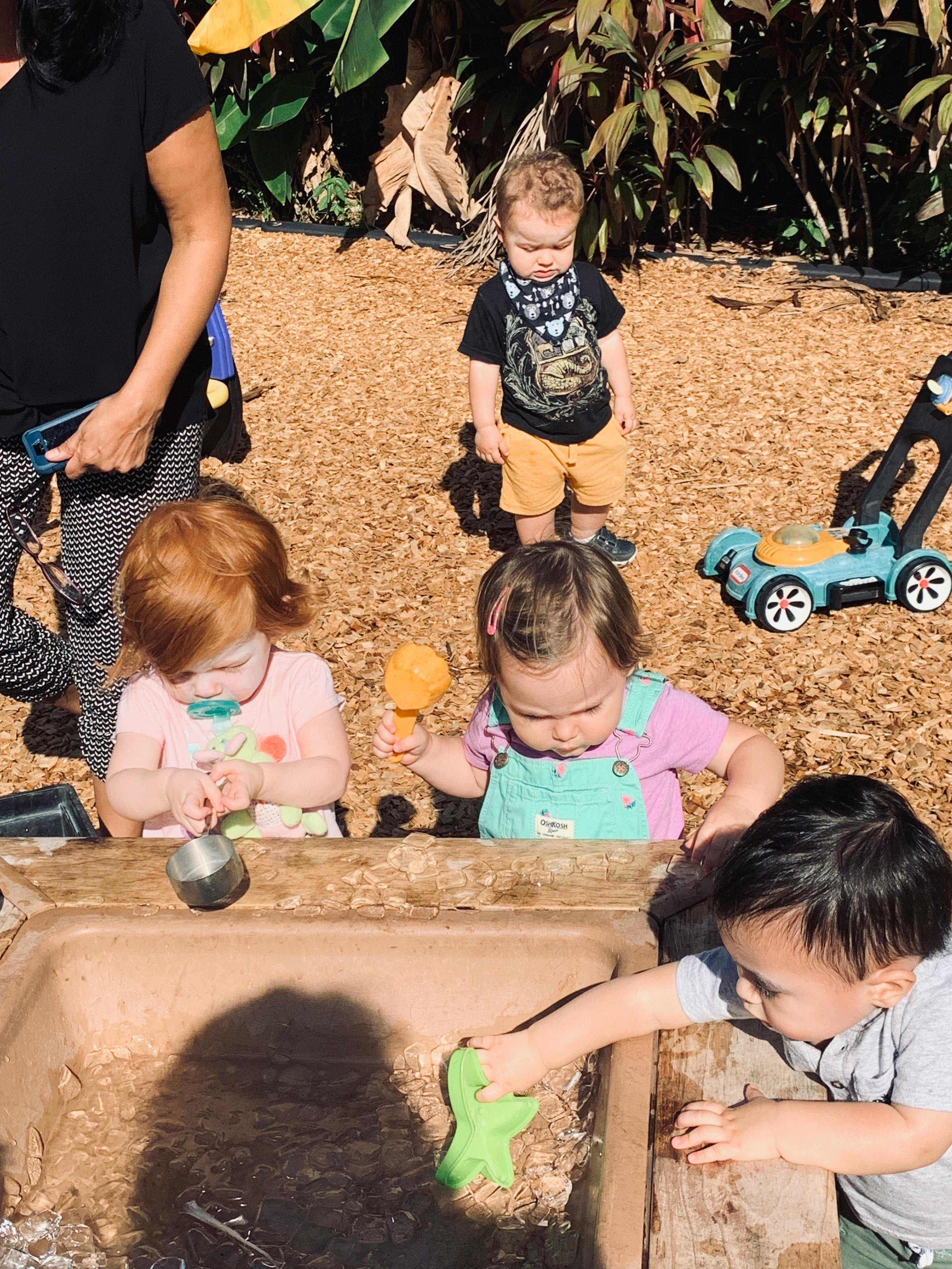 Children playing with water and toys in an outdoor setting
