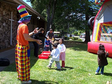 Person in clown costume making bubbles for children outdoors