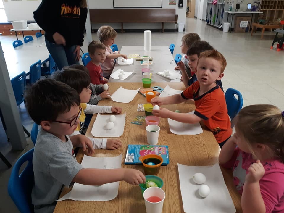 Children at a table decorating eggs with dyes