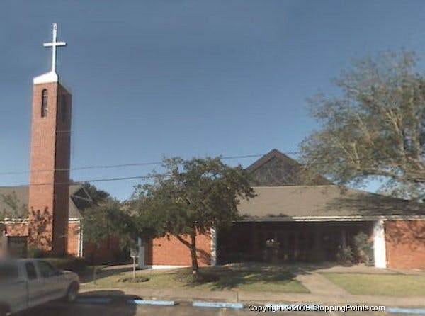 Brick church with a tall steeple and white cross