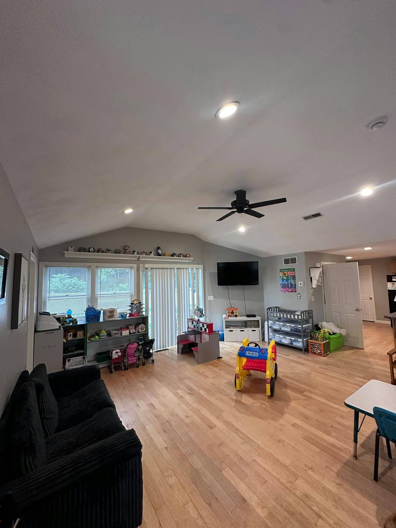 Spacious playroom with toys, a child-sized kitchen set, and a play vehicle