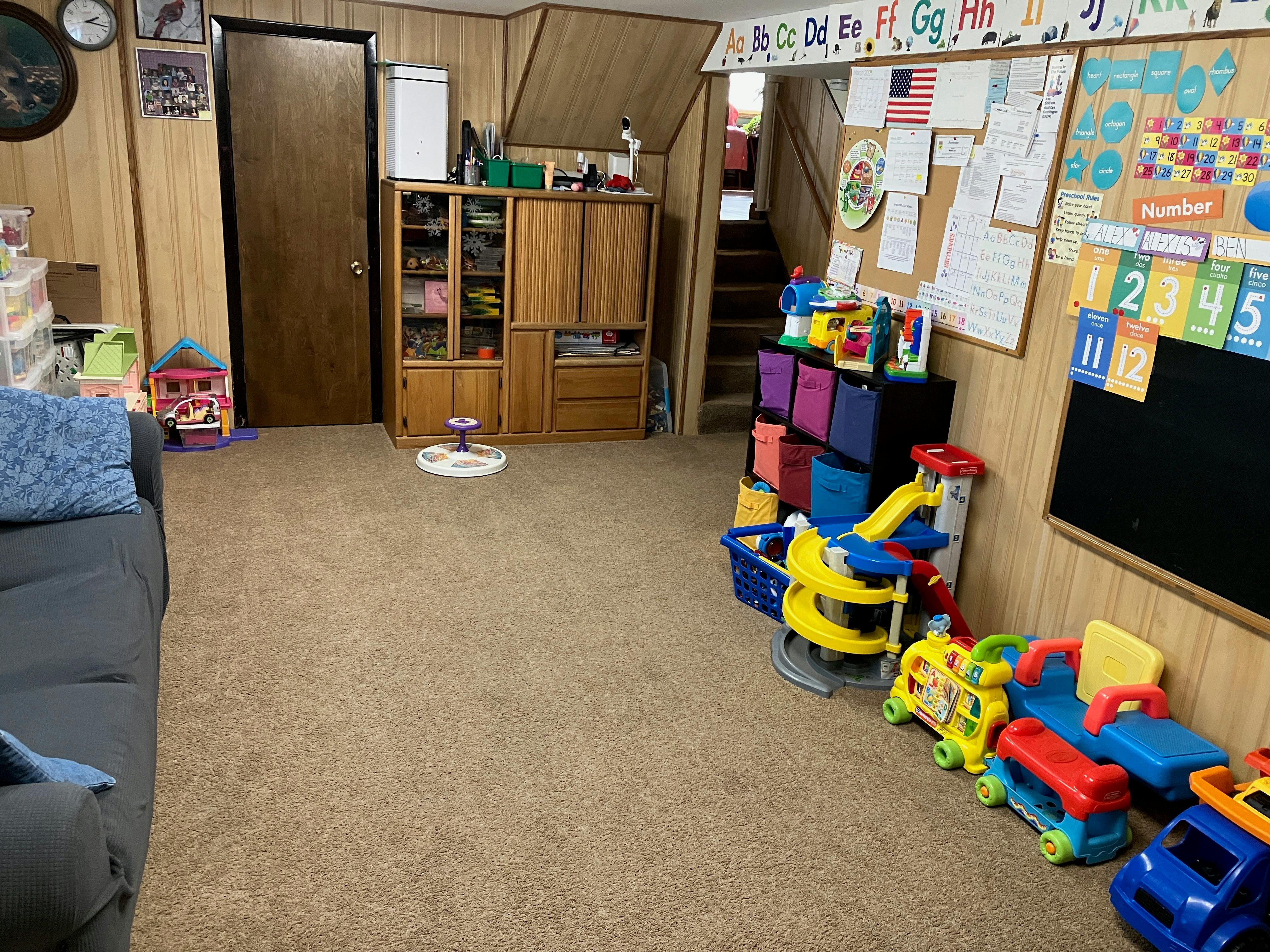 Playroom with toys, a couch, and a bulletin board