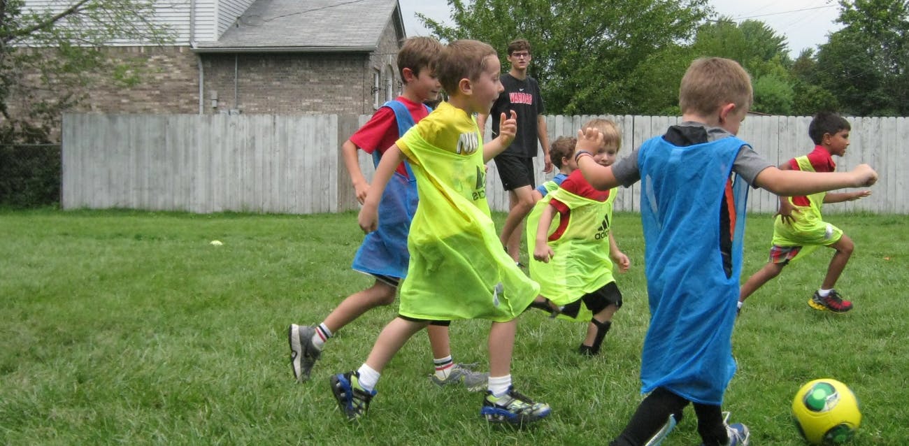 Children playing soccer on a grassy field