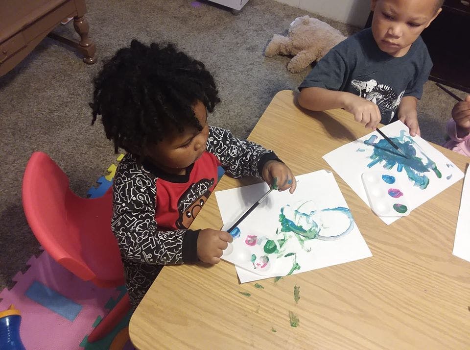 Two children painting at a table