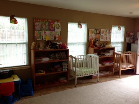 Two cribs in a room with shelves and windows