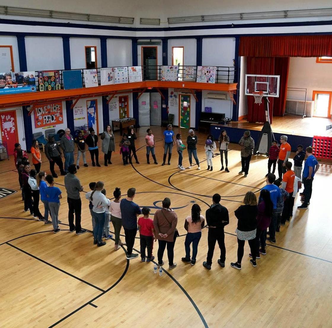 Group of people standing in a circle on a basketball court in a gymnasium