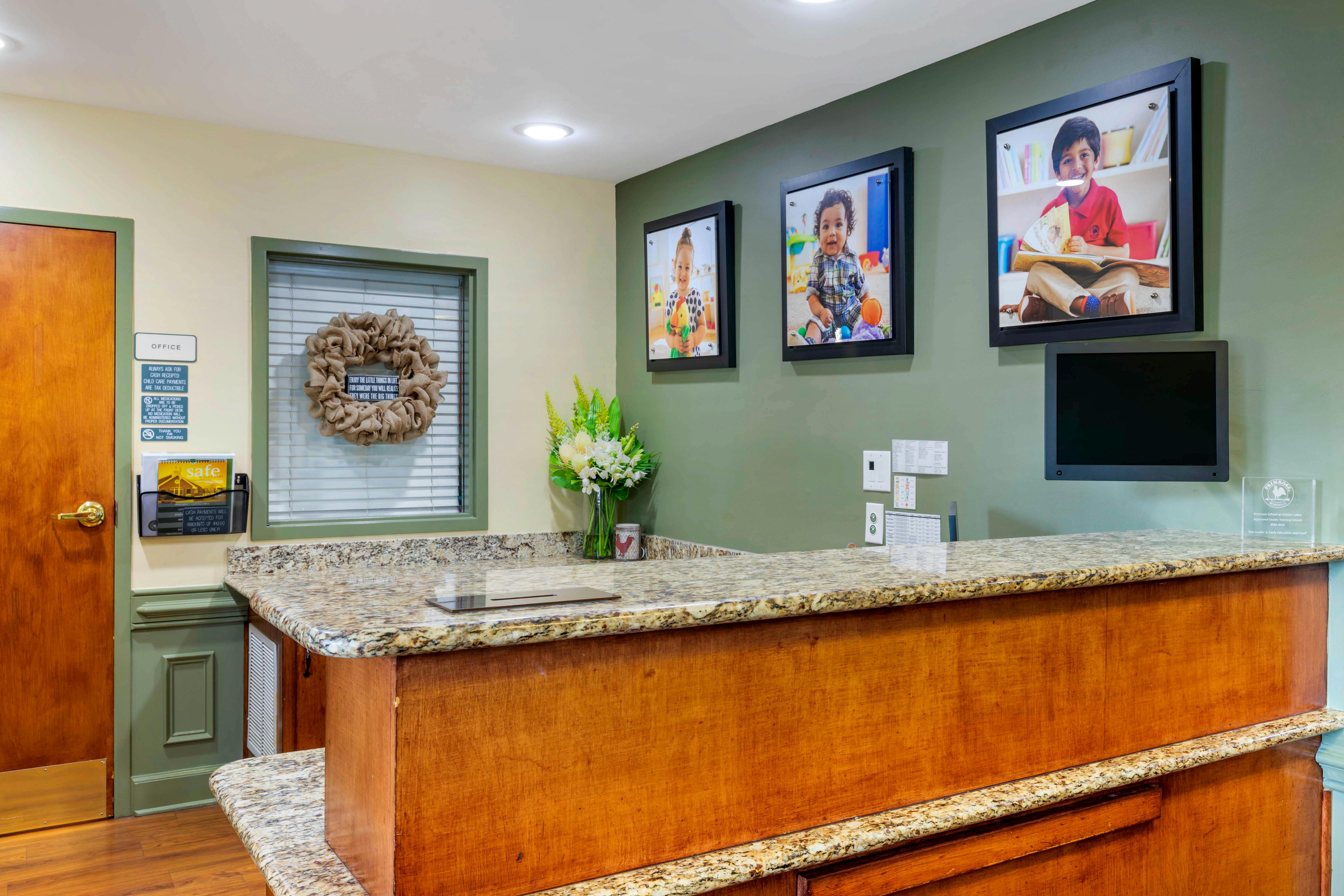 Reception desk with granite countertops and photos of children on the wall