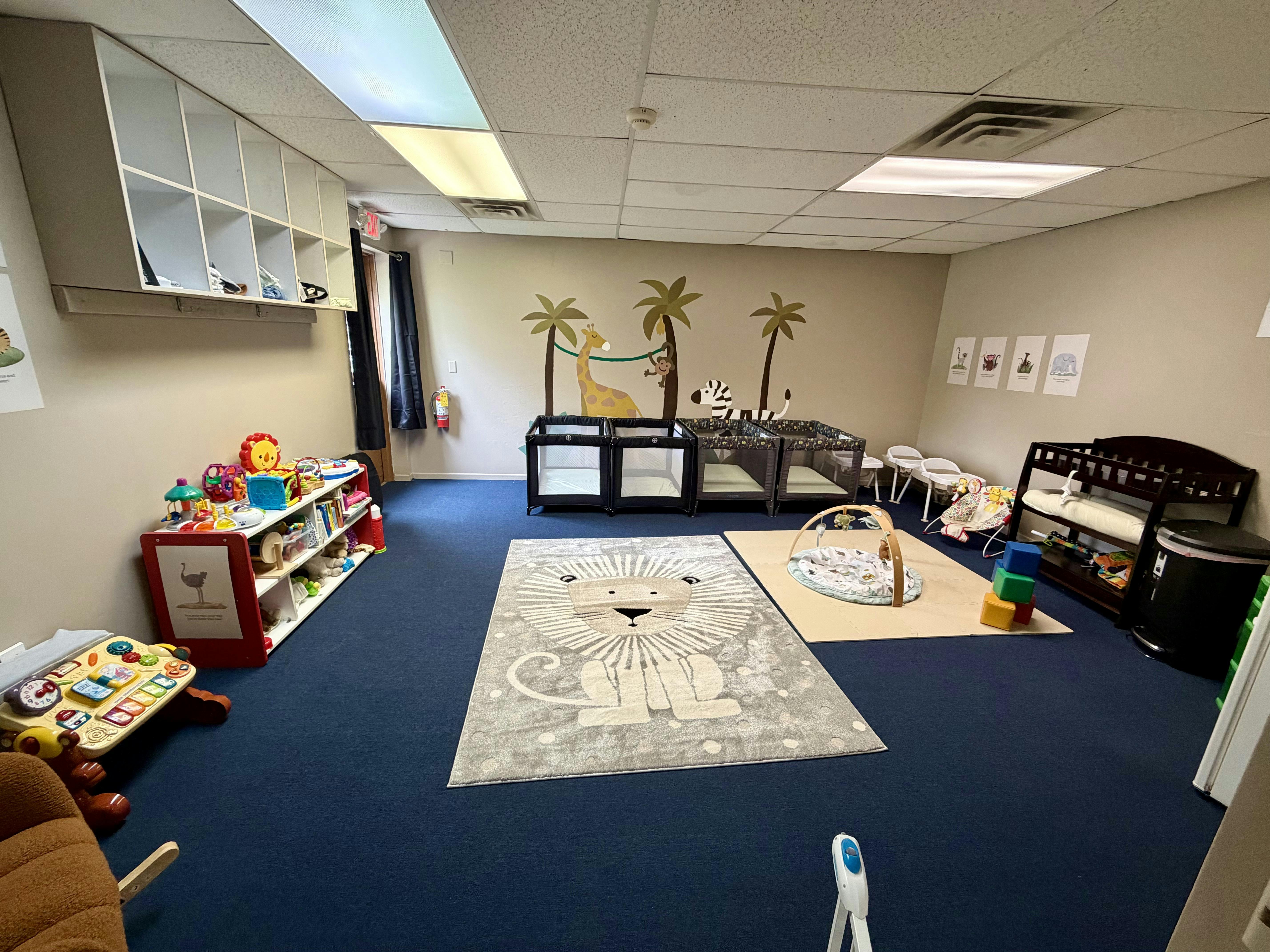 A colorful childcare classroom with various play equipment and cribs