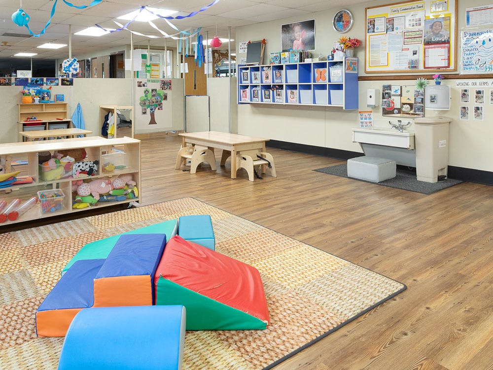 An empty early childhood classroom with soft play equipment on a rug