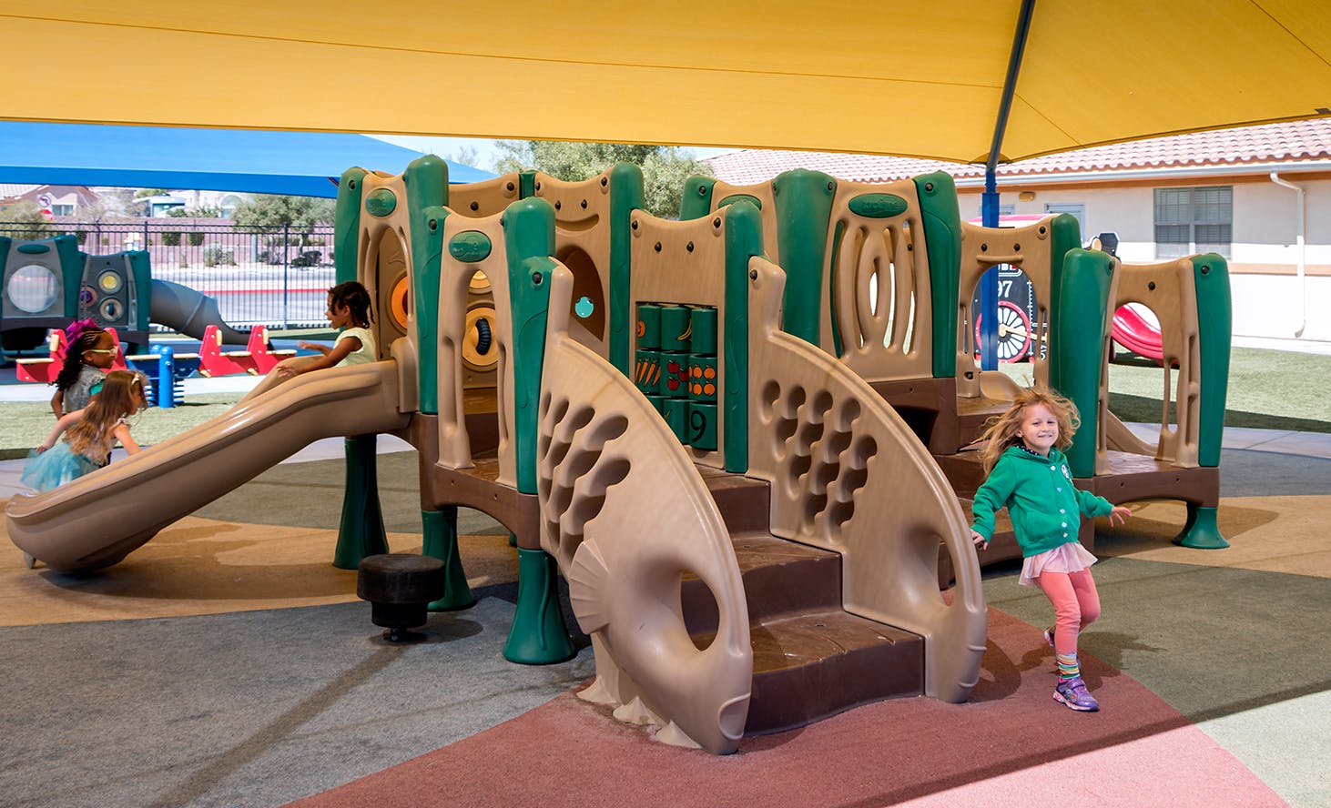 Children playing on a playground structure with slides and climbing structures