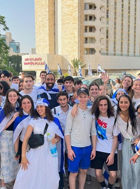 Group of young people smiling, some wearing blue and white capes
