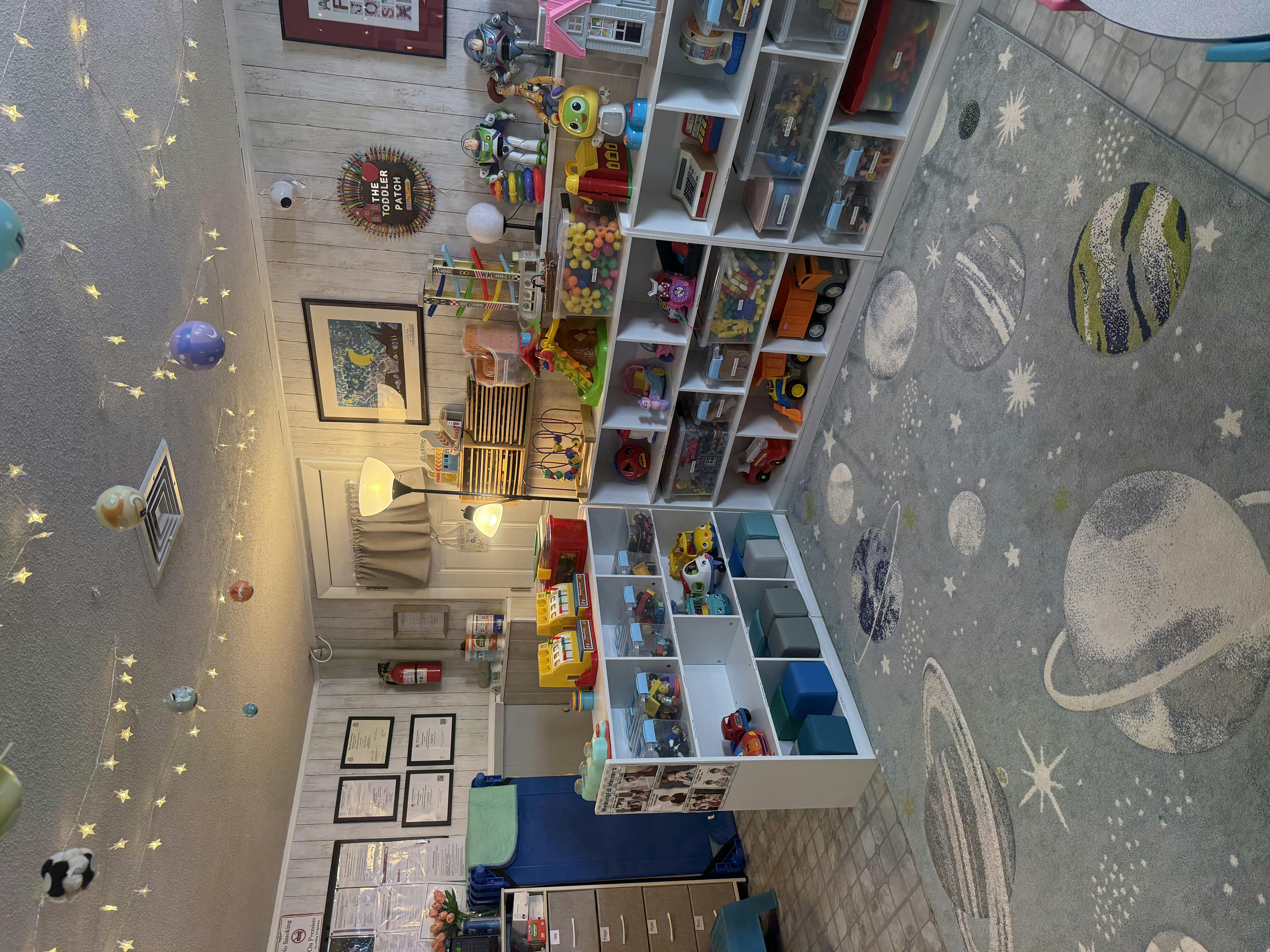 Playroom with toy shelves, a bed, and a space-themed rug