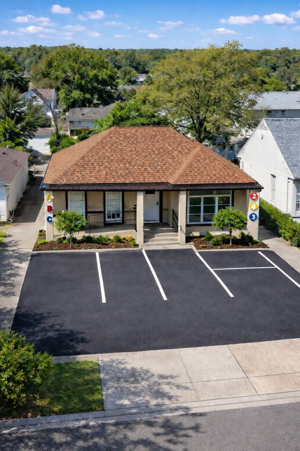 Single story building with alphabet and number signs near a paved parking lot