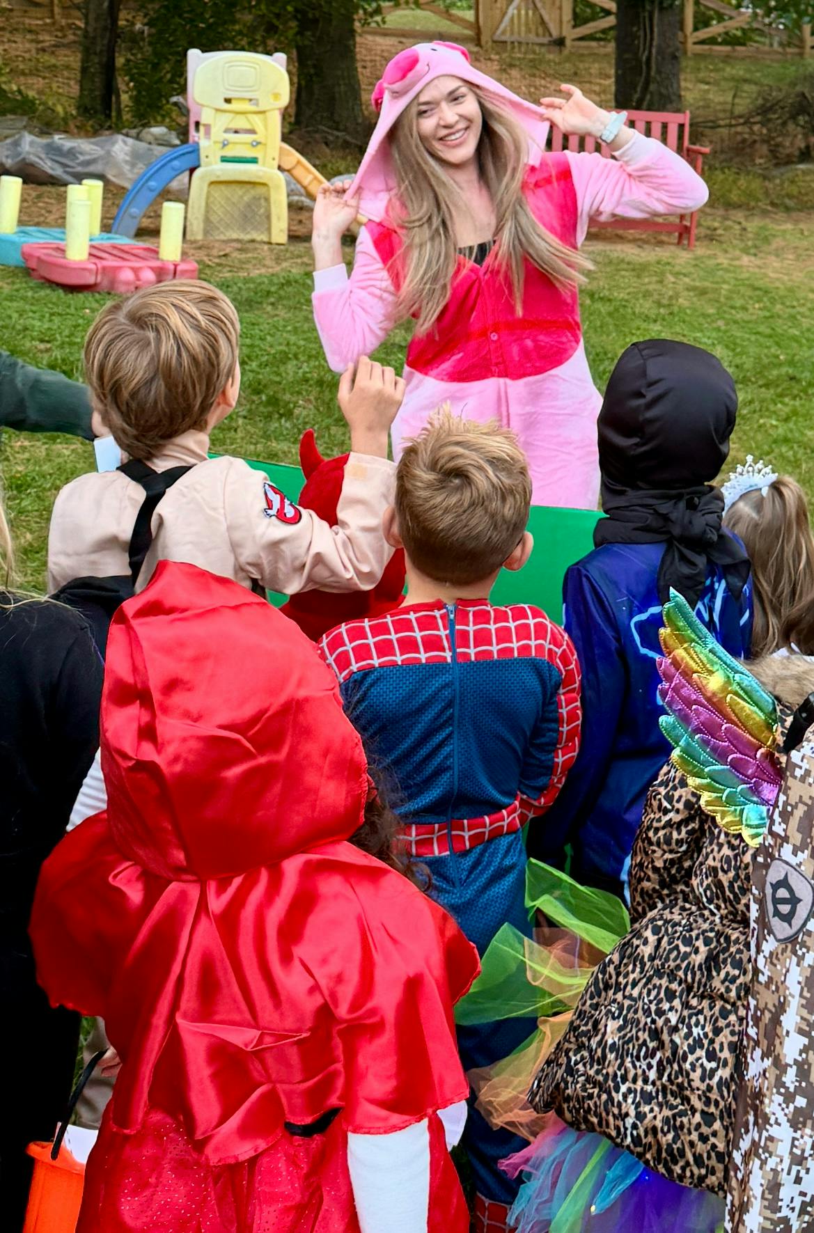 A person in a pink costume entertaining children in various Halloween costumes