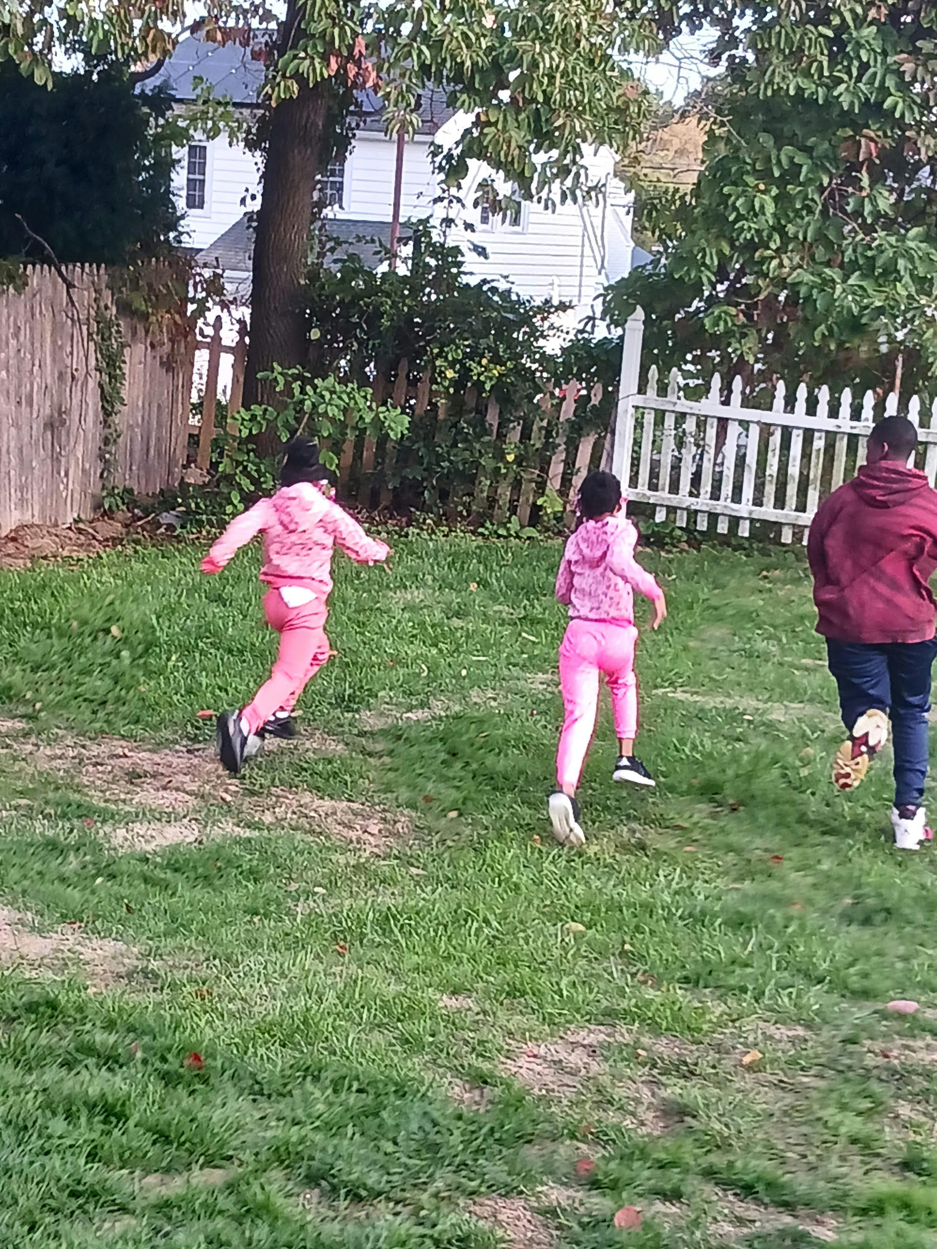 Two children and one person running on grass