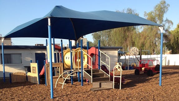 Playground with a blue shade structure over play equipment
