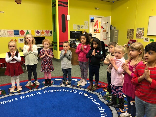 Group of children standing in a circle with hands pressed together
