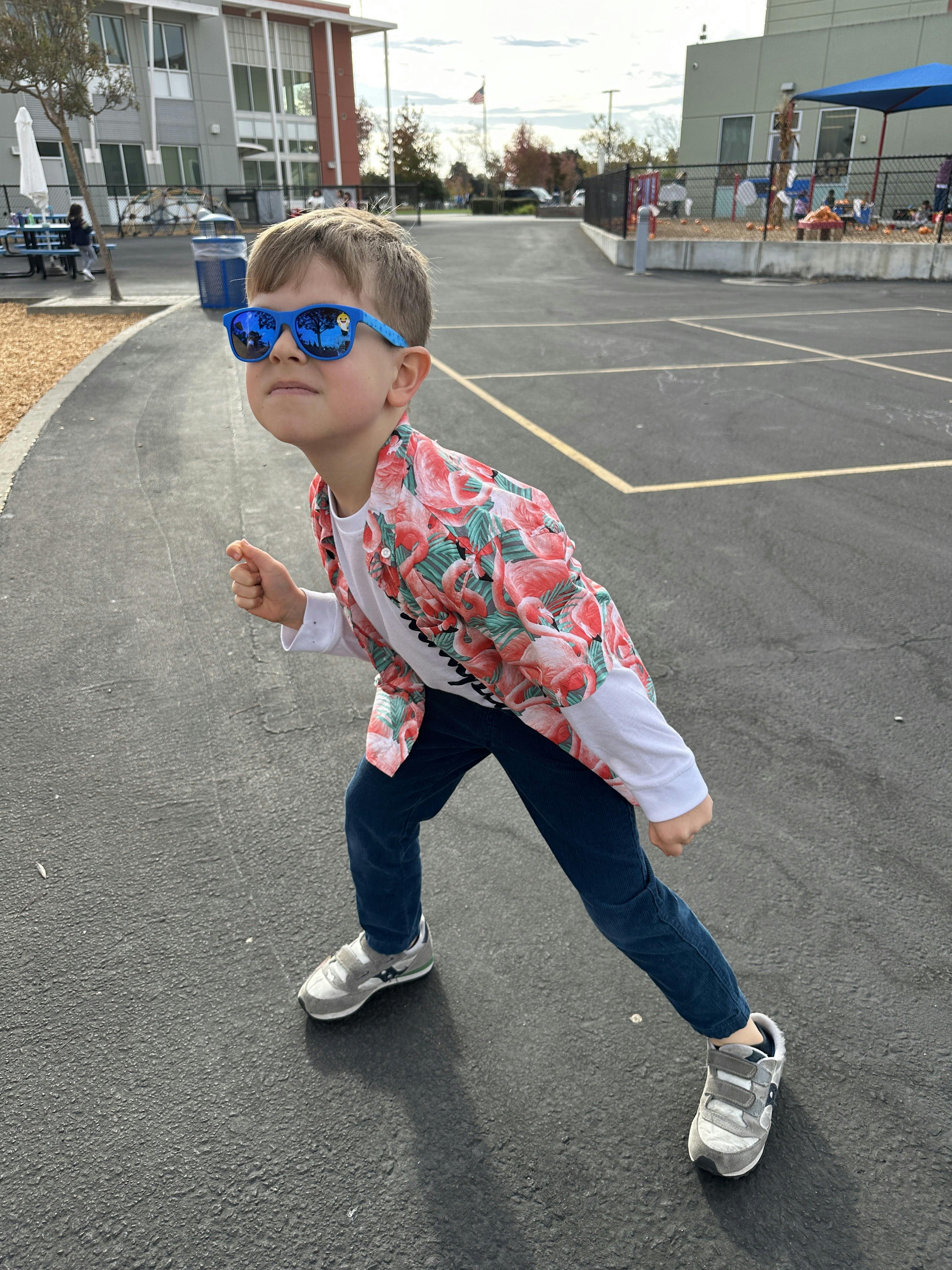 Child in sunglasses and floral jacket posing on pavement
