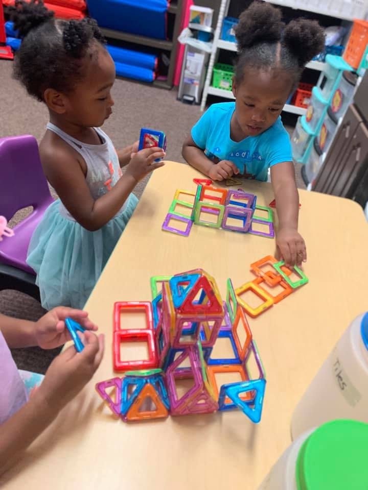 Children playing with colorful magnetic building blocks at a table