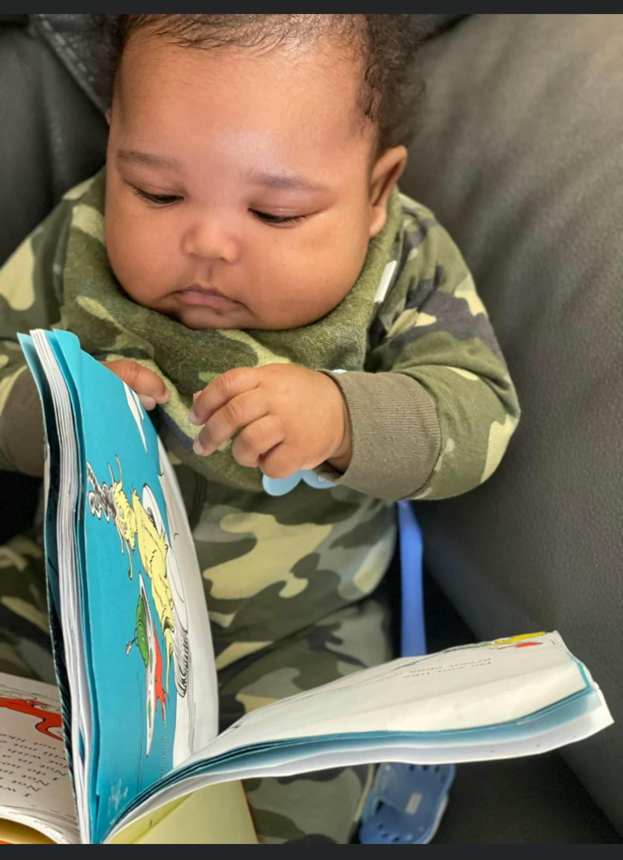 Child in camouflage clothing looking at an open book