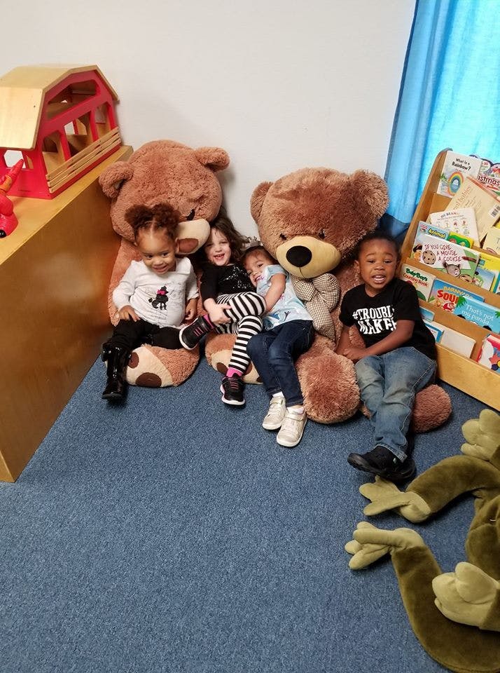 Four children sitting with large teddy bears