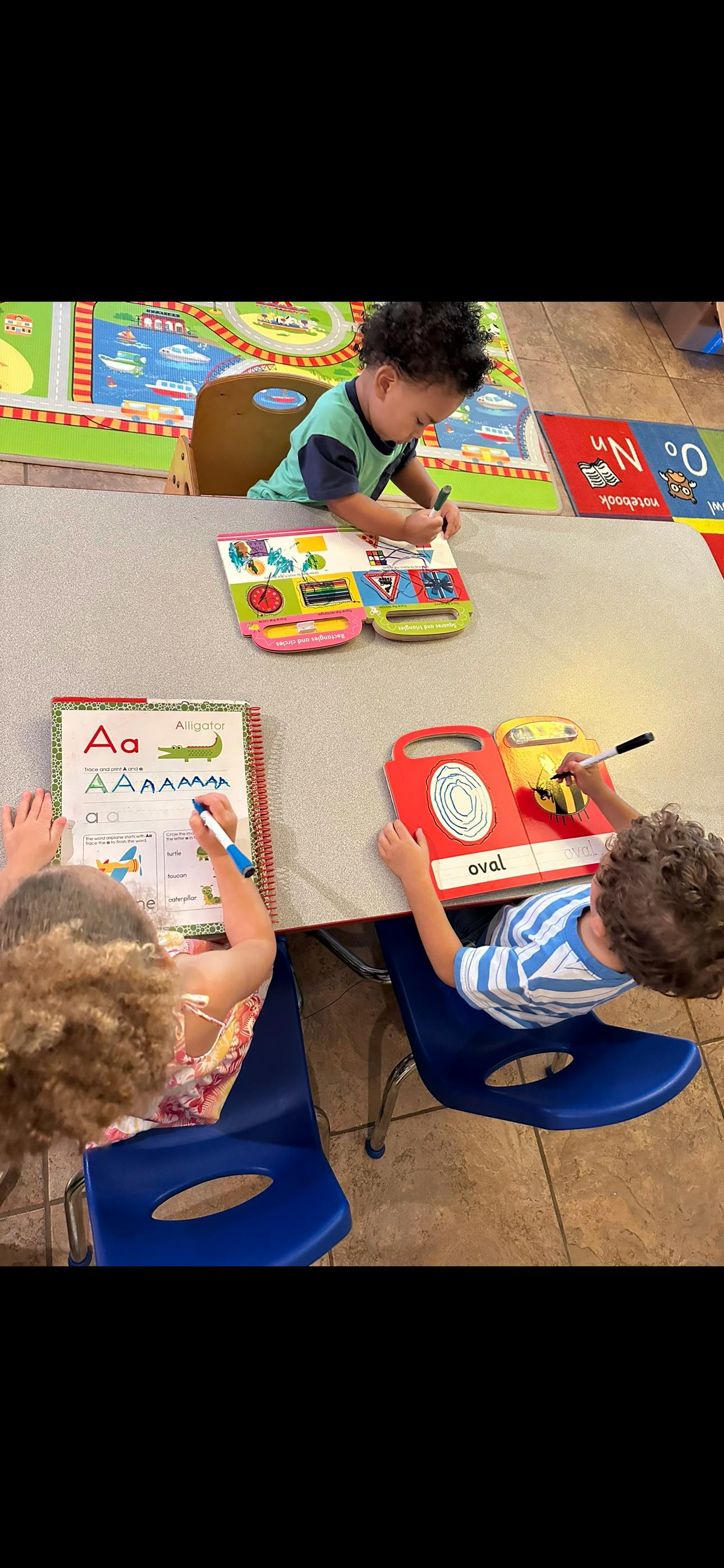 Children drawing and writing in books at a table