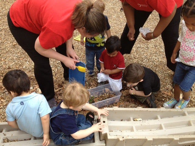 Adults and children playing with dirt and containers outdoors