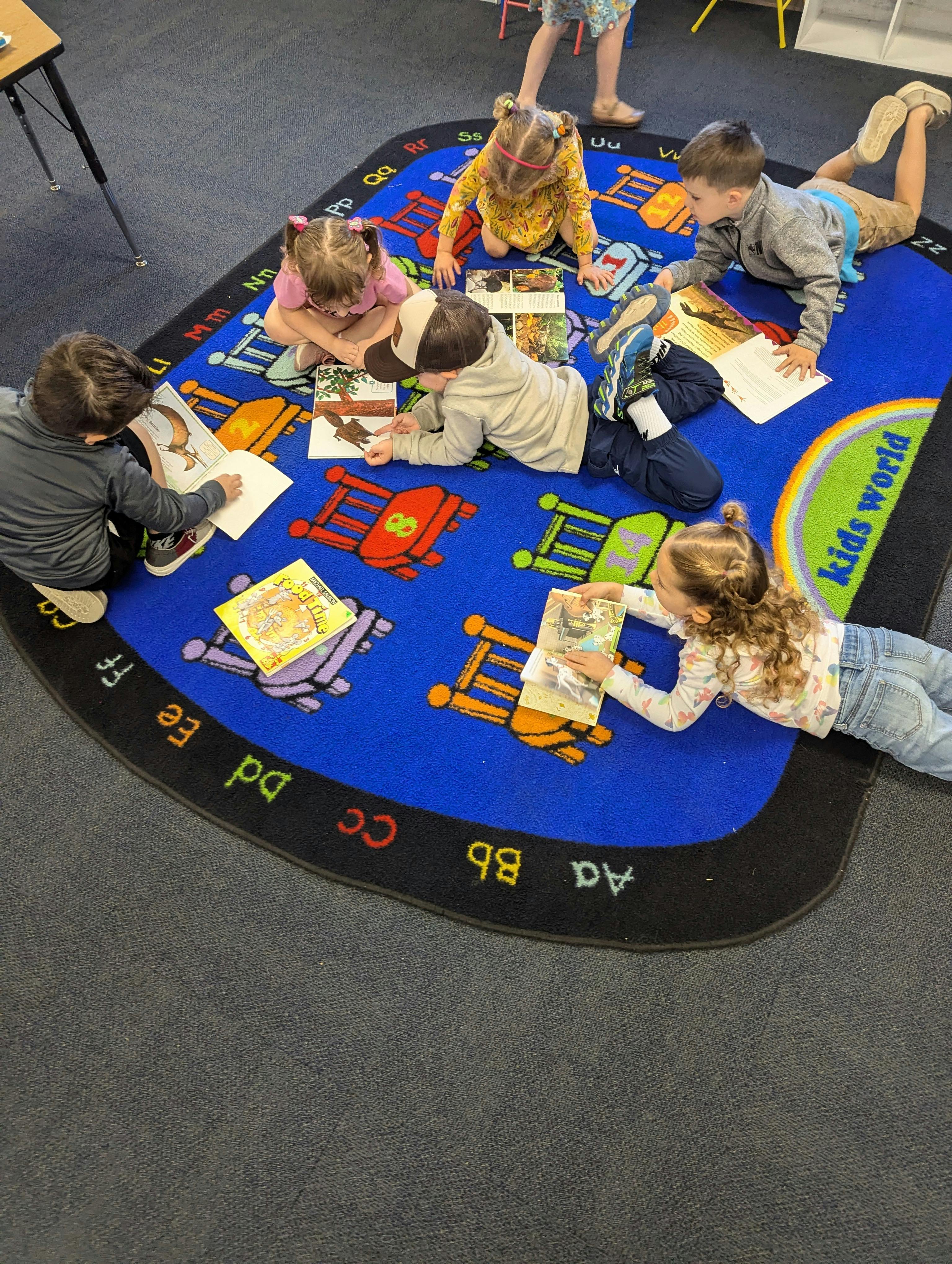 Children reading books on a rug in a classroom
