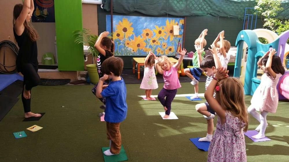 Adult and children doing yoga poses outdoors
