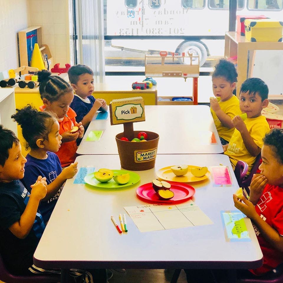 Children sitting at tables eating fruit