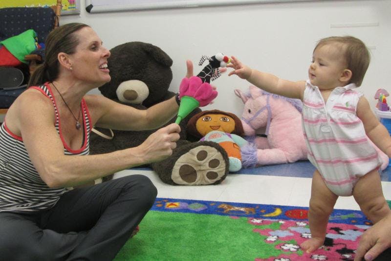 Person playing with a child reaching for a toy