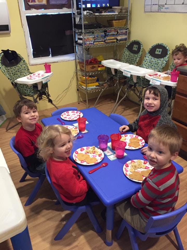 Children sitting at a blue table with plates of food