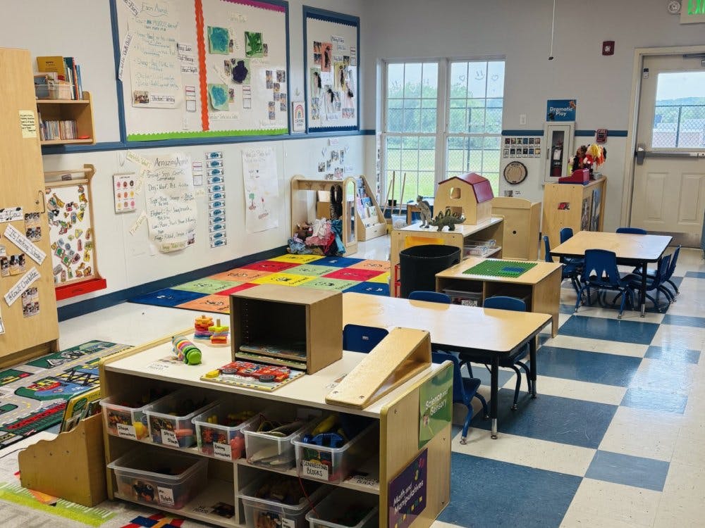 Classroom with small tables, chairs, colorful rugs, and display boards
