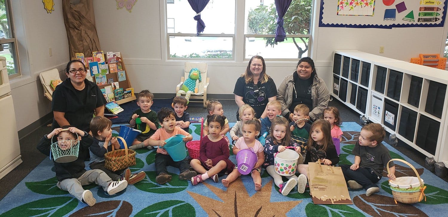 People and children sitting on a rug in a classroom