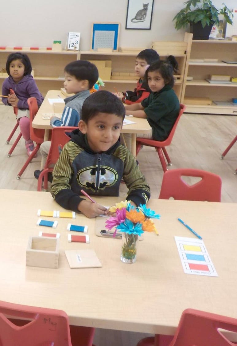 Child drawing at a table with other children in a classroom