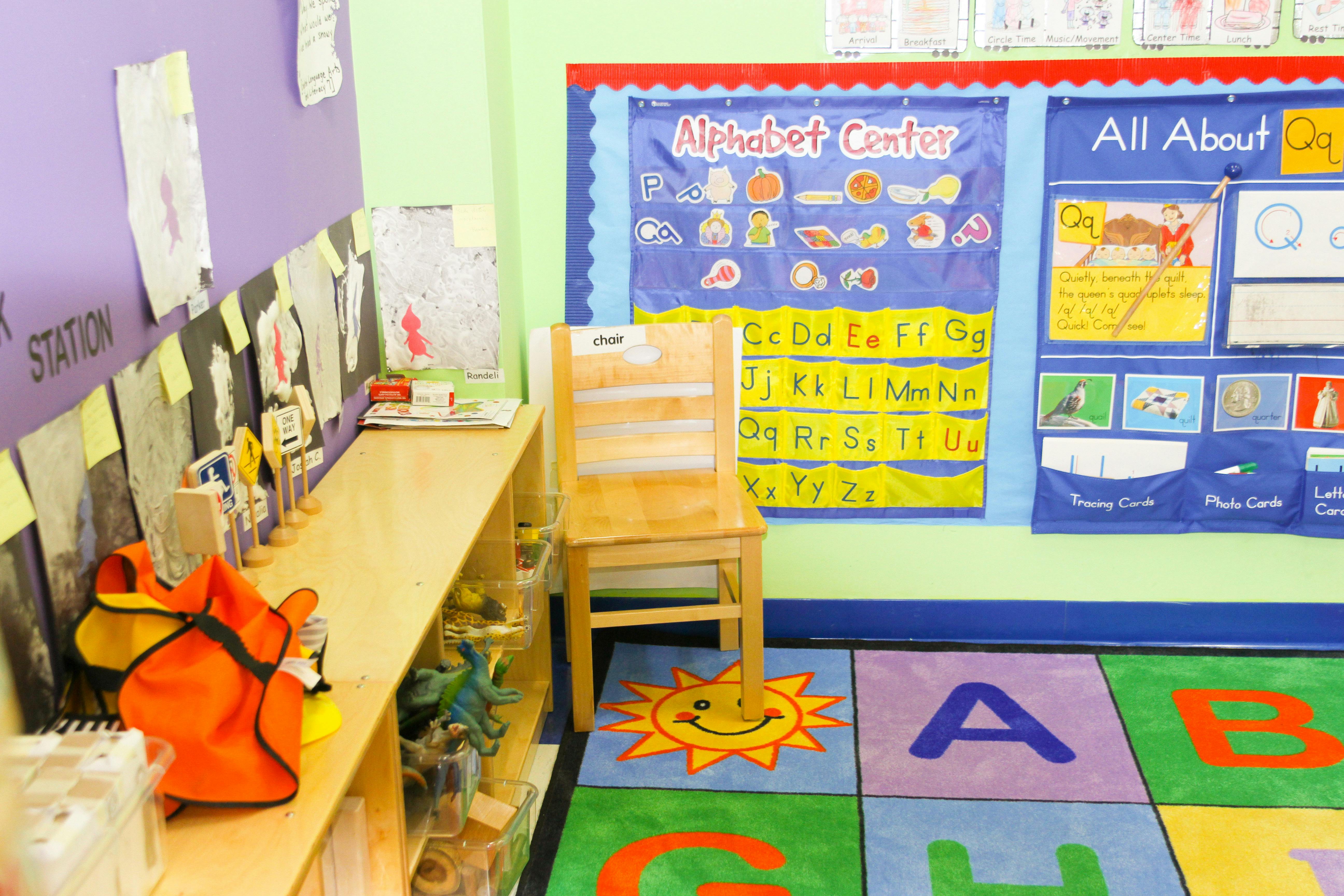 Classroom with alphabet chart, wooden chair, and alphabet rug