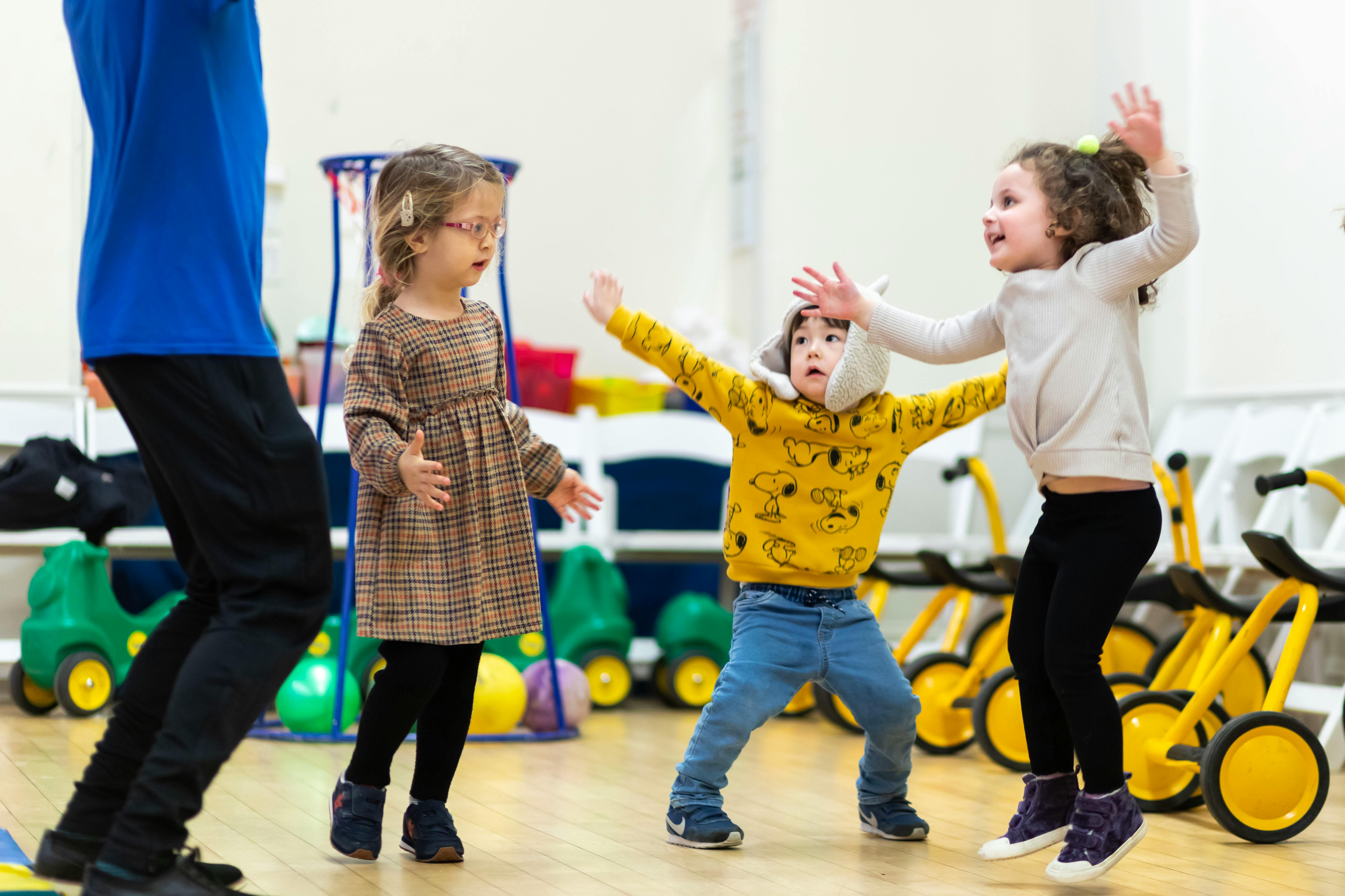 Three children playing indoors, one person partially visible