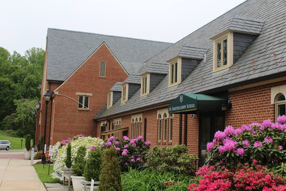 Brick building with dormer windows and a green awning over an entrance