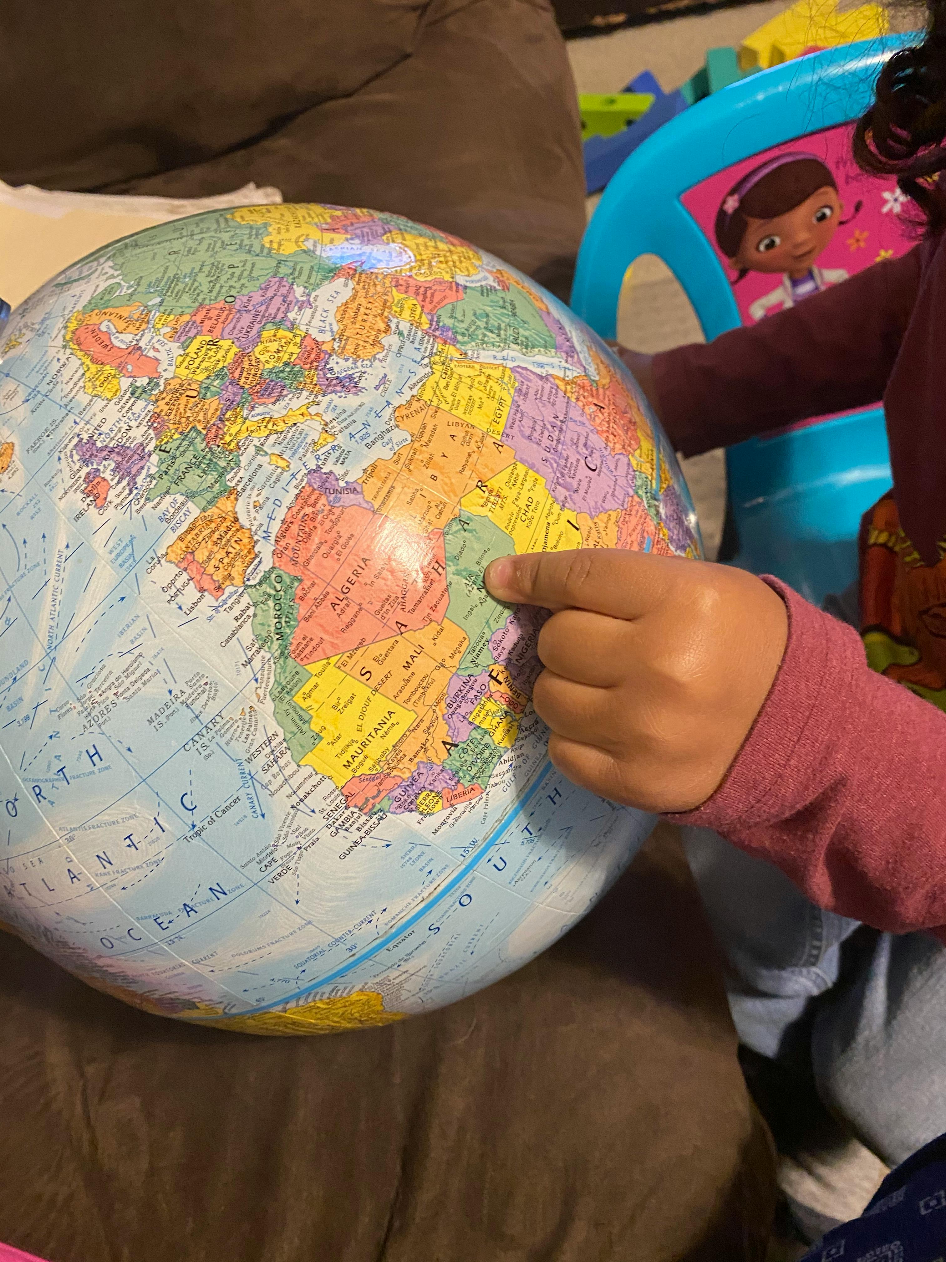 Child's hand pointing at a globe