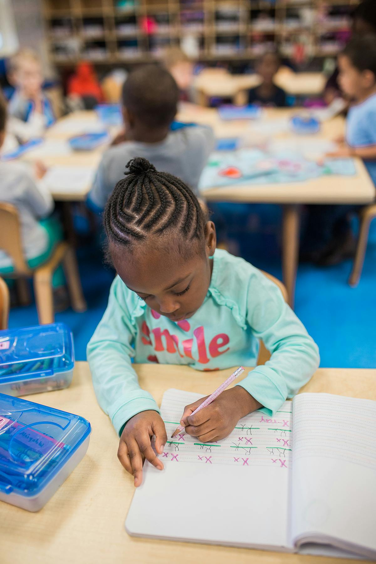 Child writing in a notebook in a classroom