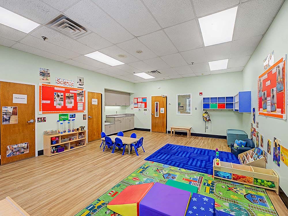Classroom with small table and chairs, storage shelves, and colorful rugs