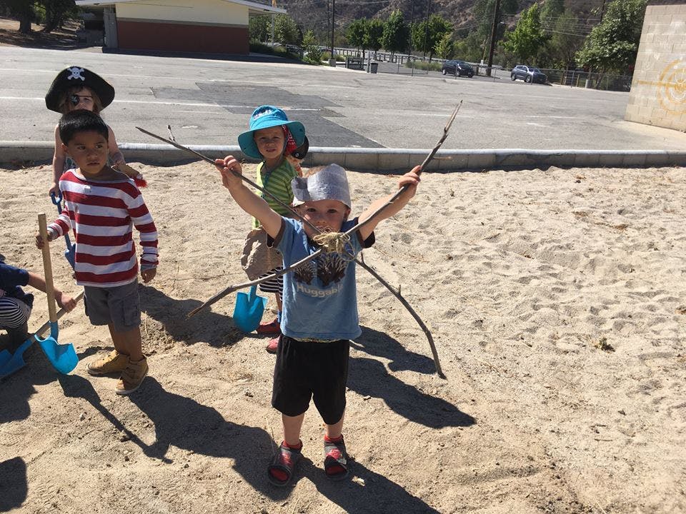 Children playing in a sandbox with sticks and shovels