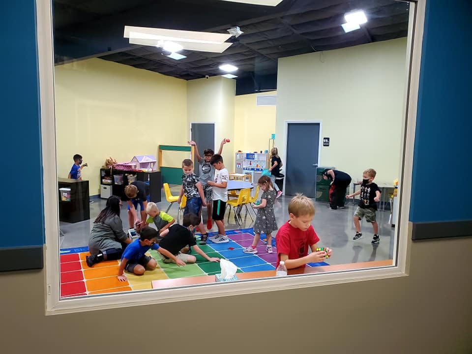 Children playing on a colorful mat in a large room