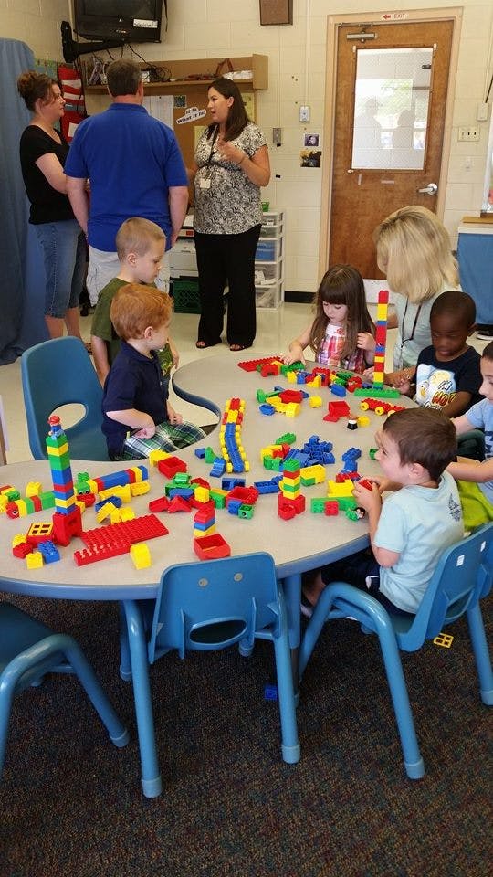 Children playing with colorful building blocks at a table in a classroom